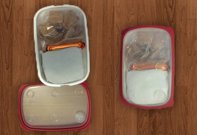 Open container with crackers, granola bar, and sandwich and  closed container, with little empty space inside.